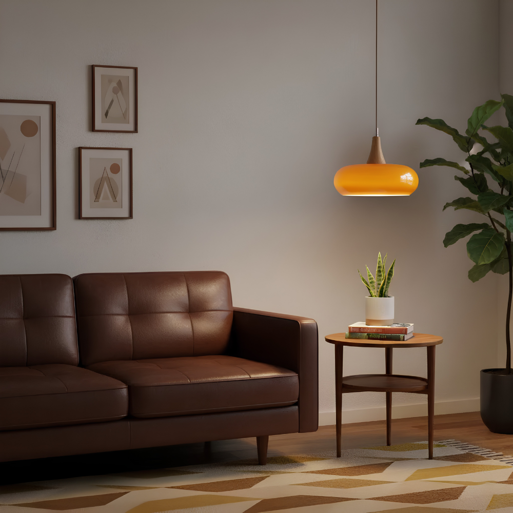 Pomarańczowa lampa wisząca szklana nad stolikiem obok kanapy w salonie