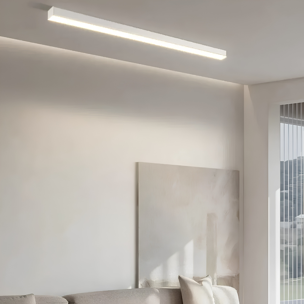 Biała liniowa lampa sufitowa LED nad kanapą w jasnym salonie