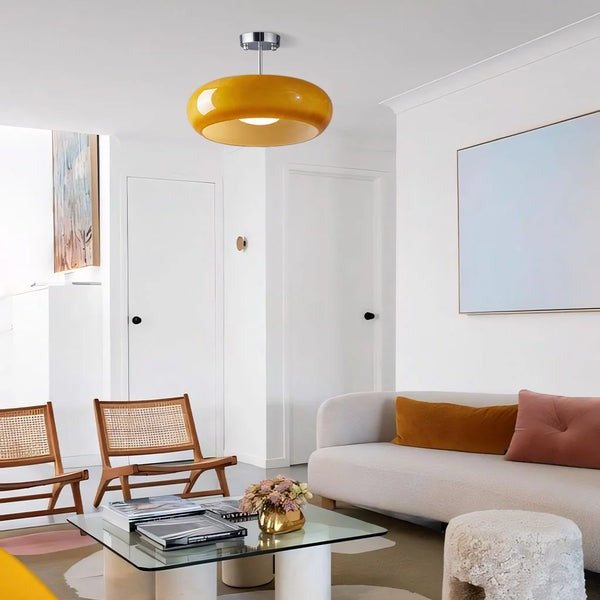 Szklana lampa sufitowa w chromie i pomarańczu w salonie nad kanapą i fotelami