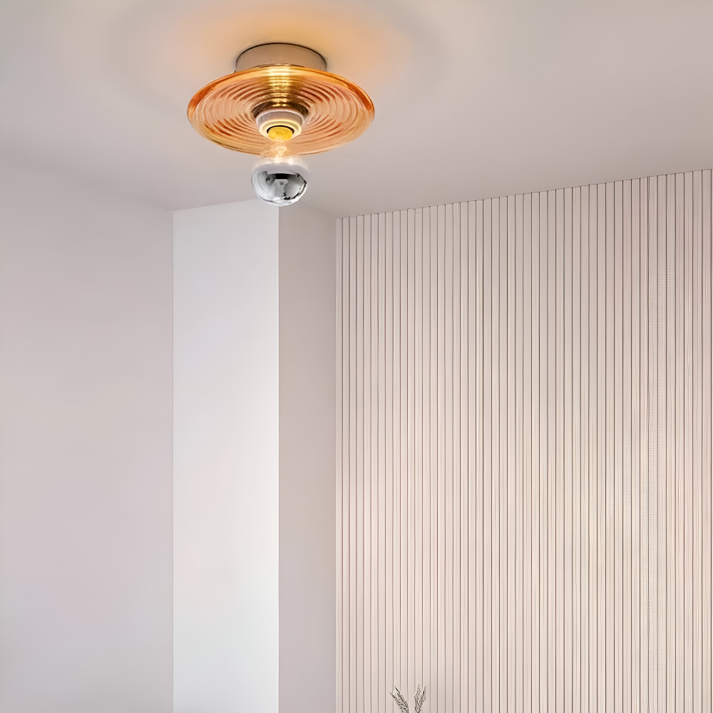Pomarańczowa lampa zamontowana na suficie przy ryflowanej ścianie