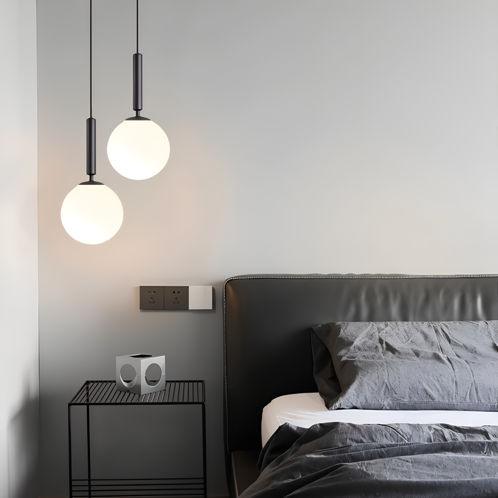 Dwie czarne lampy wiszące kule obok łóżka w sypialni