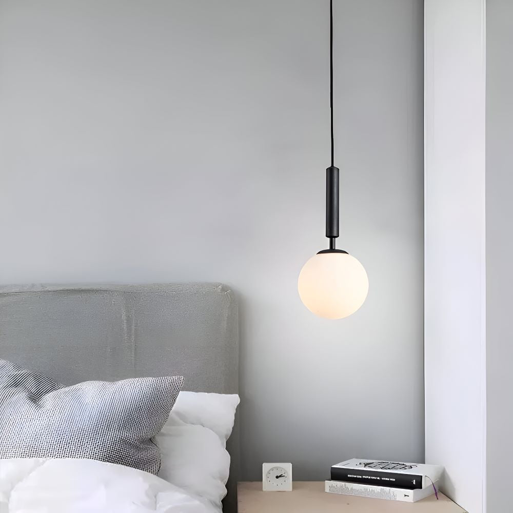 Czarna lampa wisząca kula z mlecznego szkła przy łóżku