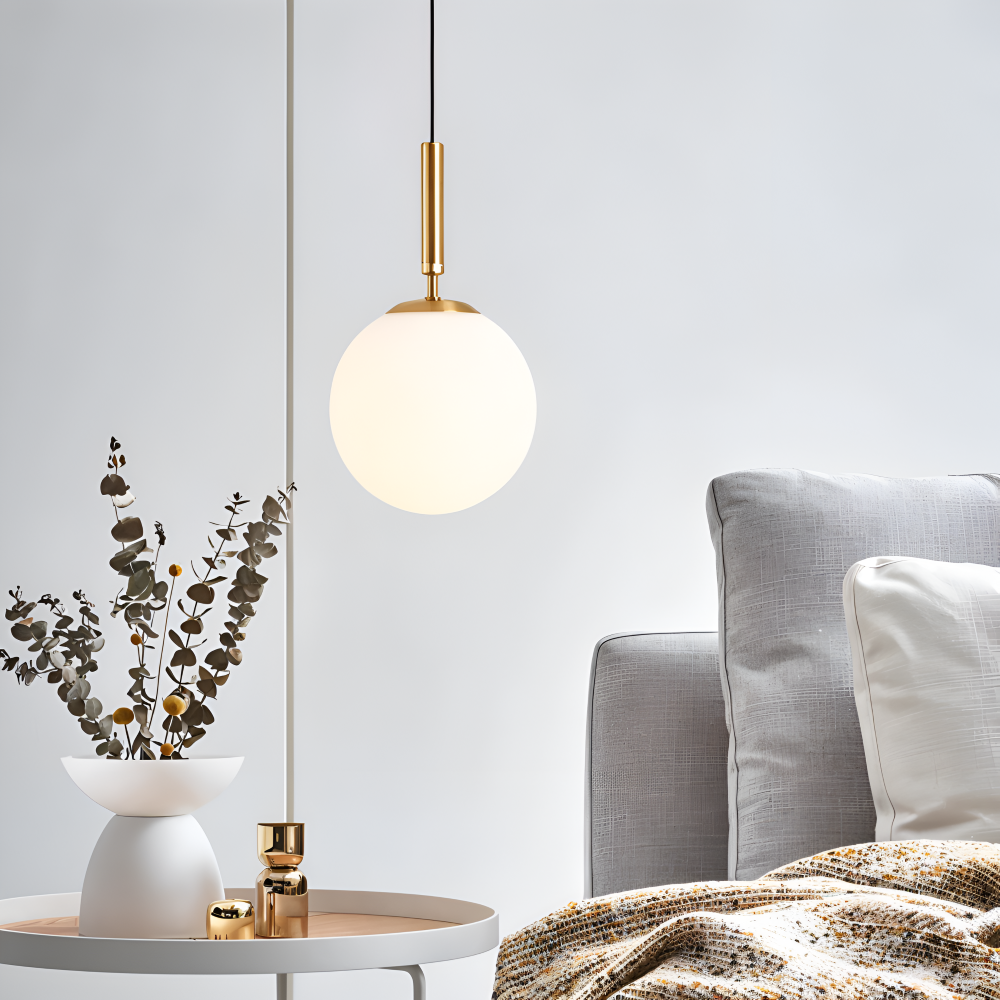 Złota lampa wisząca z dużą mleczną kulą nad stolikiem