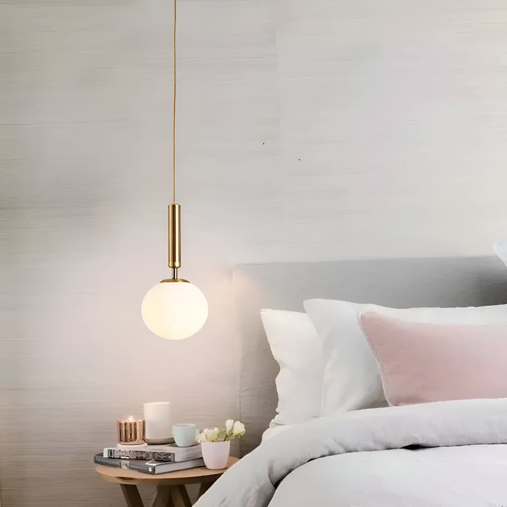 Złota lampa wisząca kula nad szafką nocną
