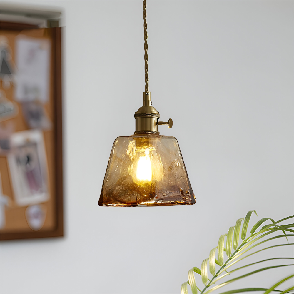 Zapalona lampa wisząca ze stożkowym bursztynowym kloszem przy tablicy korkowej