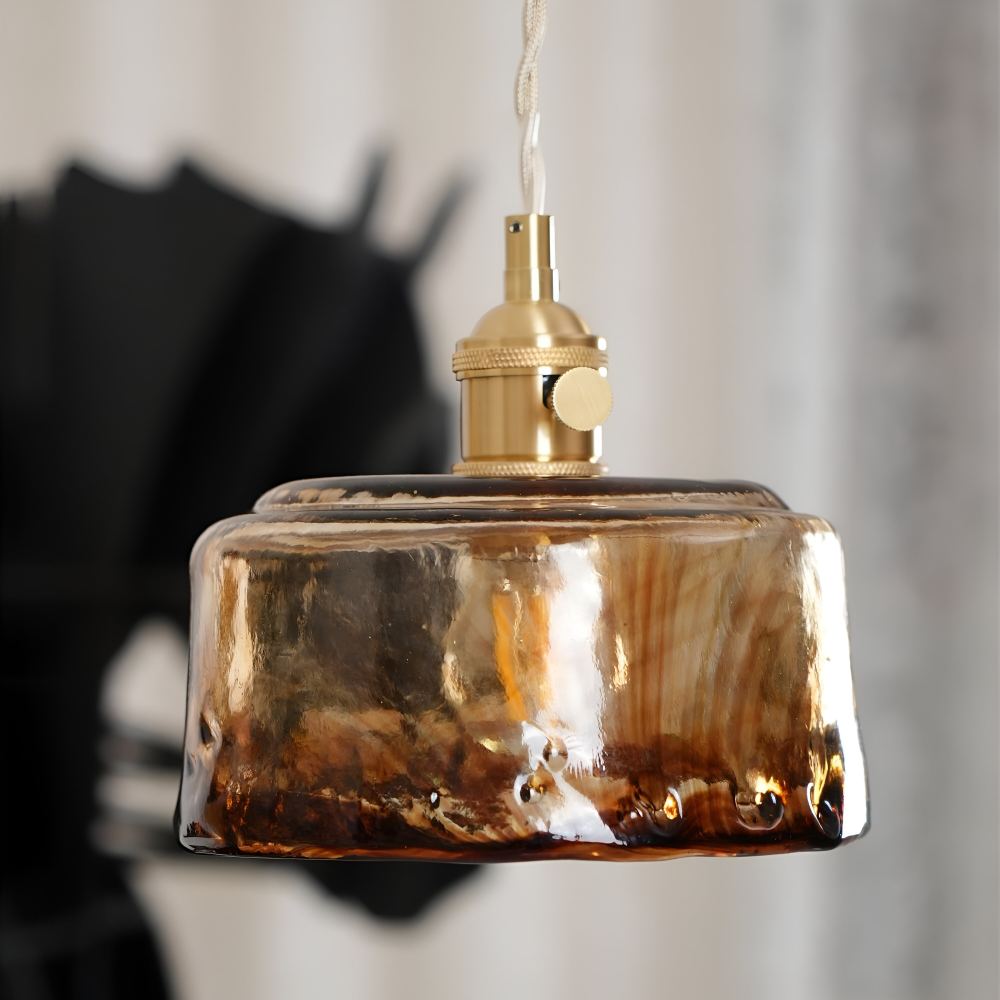 Lampa wisząca ze szklanym kloszem w ciemniejszym wnętrzu, ujęcie z boku
