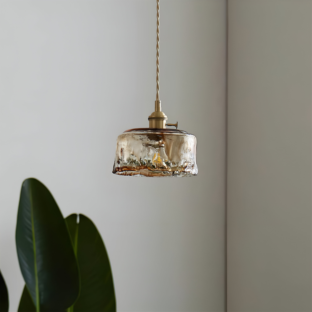 Lampa wisząca z niskim kloszem na tle ściany i zielonych liści