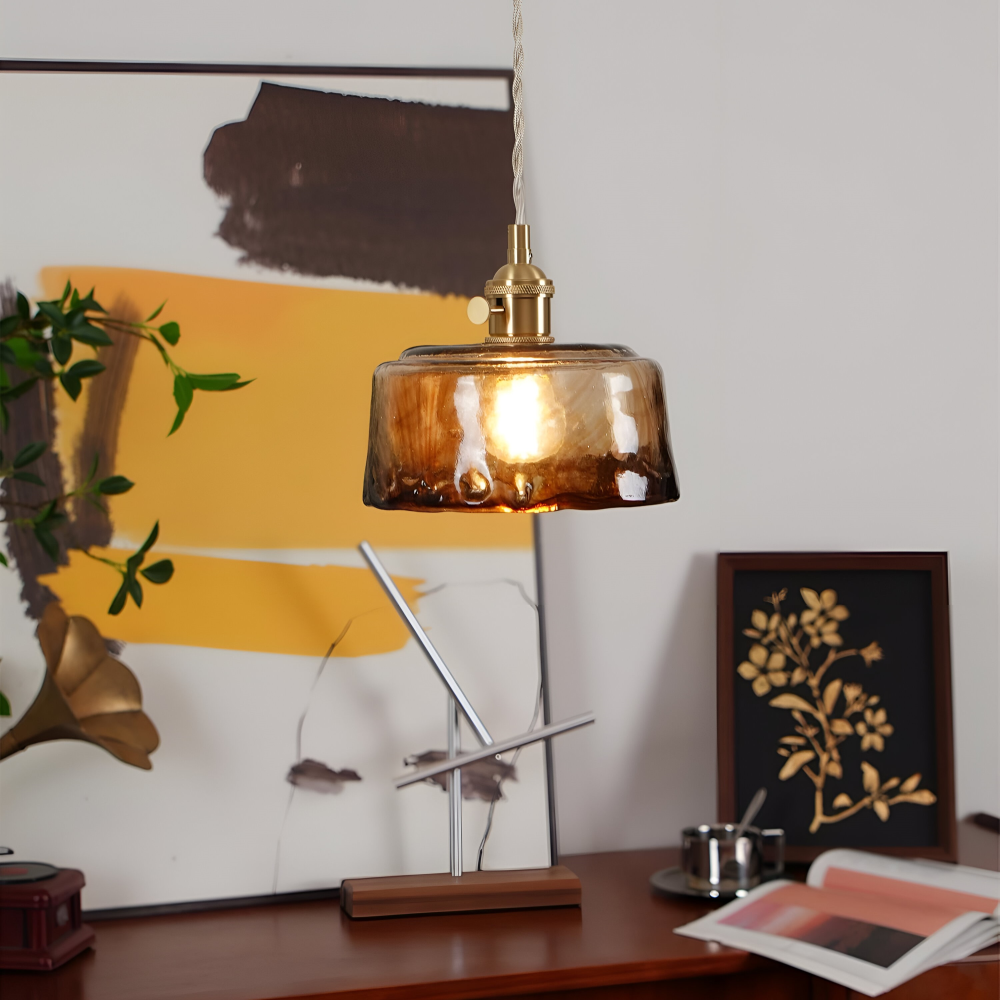 Lampa wisząca z szerokim bursztynowym kloszem nad drewnianym biurkiem