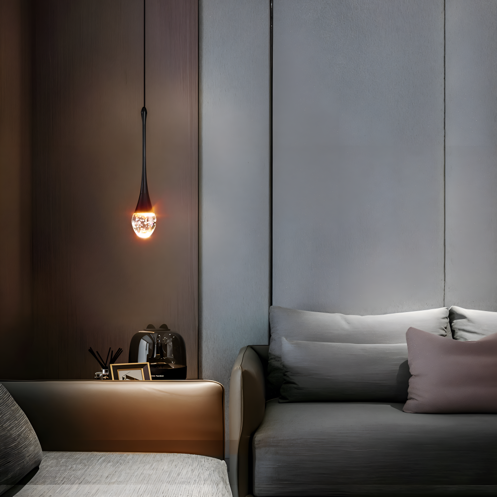 Zapalona złota lampa kropla nad szarą sofą w ciemnym wnętrzu