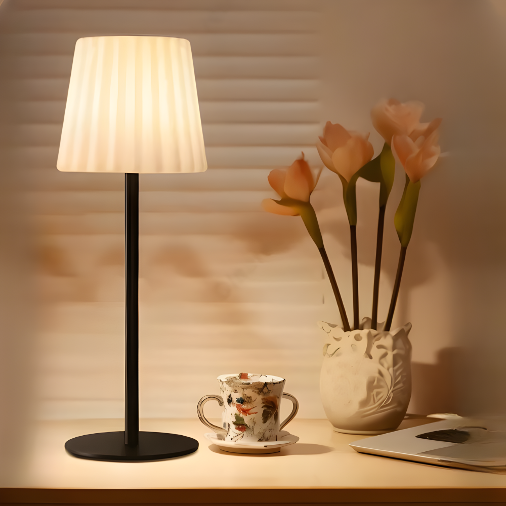 Lampa stołowa z karbowanym kloszem obok kwiatów