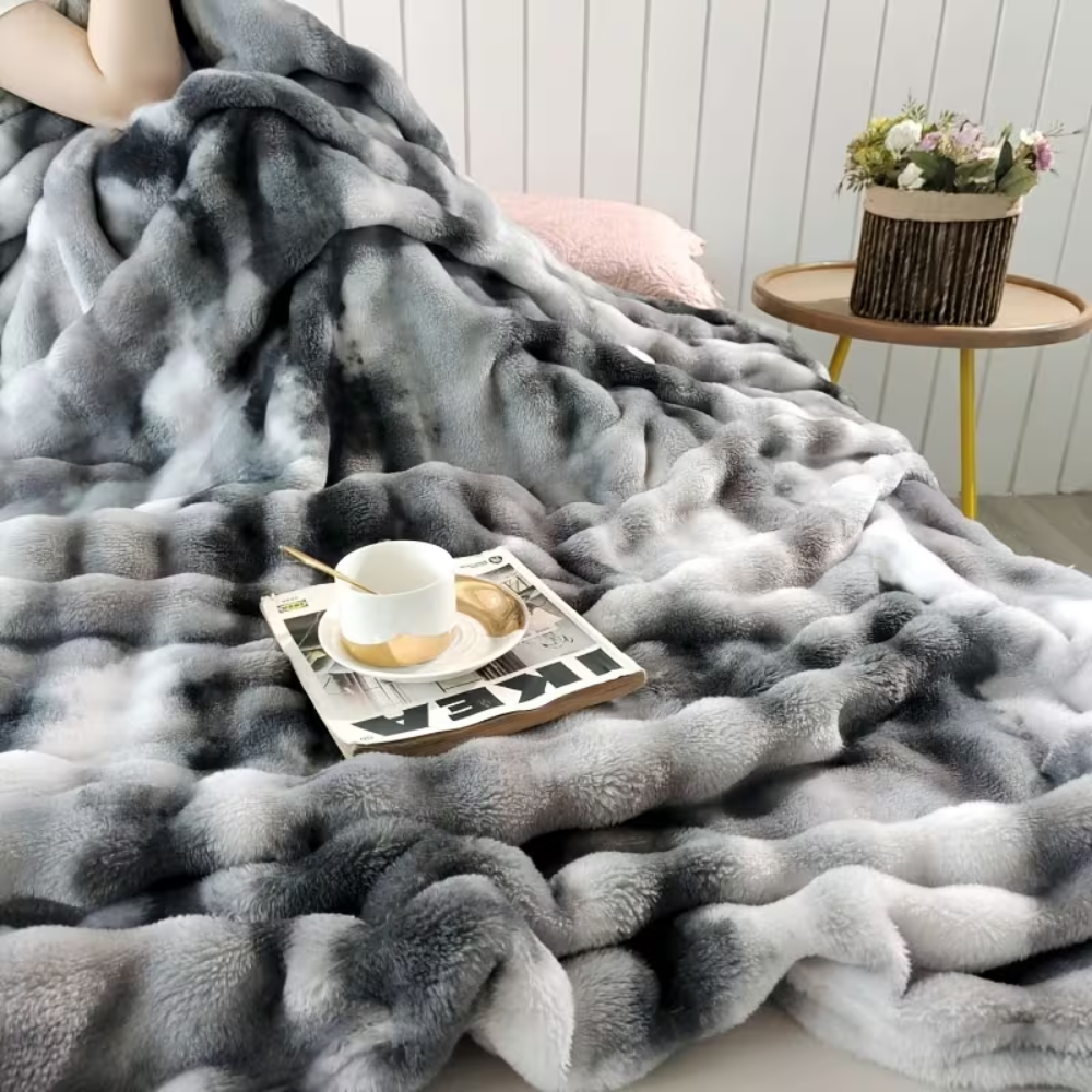 Koc pluszowy tie-dye złożony na łóżku